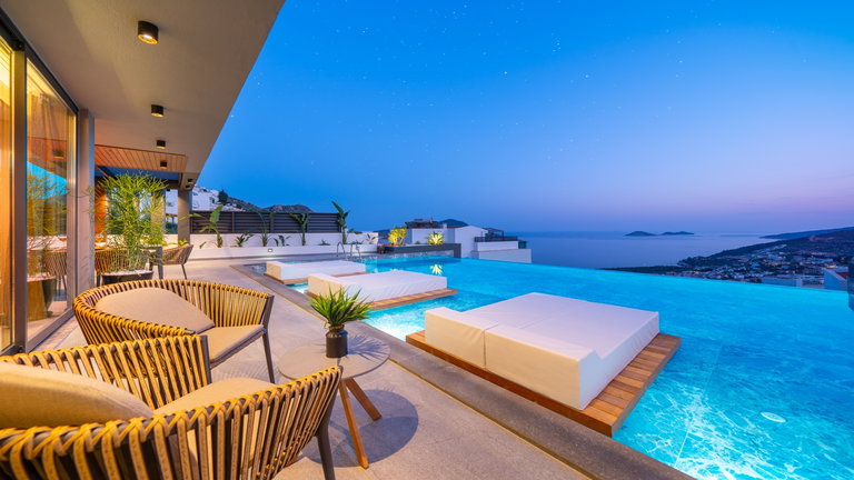 Villa Supernova's infinity pool and terrace above Kalkan bay at dusk